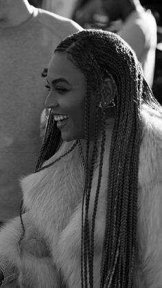 a black and white photo of a woman with long braids in her hair smiling