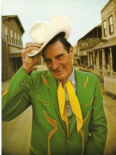 a man in a green suit and yellow tie with a hat on top of his head