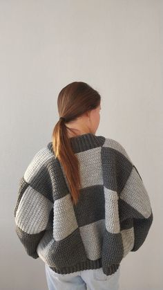 a woman with her back turned to the camera, wearing a gray and white checkered sweater