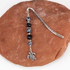 a turtle charm on a rock with a silver bar attached to it's end