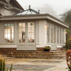 a white house with glass windows and steps leading up to the front door on a foggy day