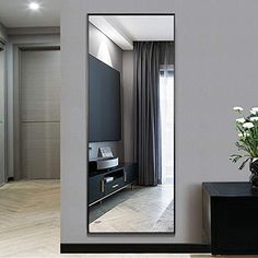 a large mirror sitting on top of a wooden floor next to a vase filled with flowers