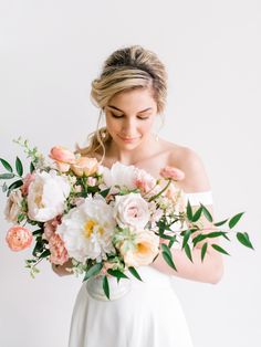 a woman holding a bouquet of flowers in her hands and looking down at the camera