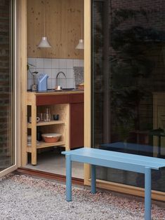 a blue bench sitting in the middle of a patio next to a kitchen and dining area