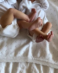 a baby laying on top of a white blanket