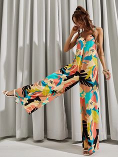 This stylish Backless All Over Print Wide Leg Cami Jumpsuit is perfect for your next warm-weather getaway. The Boho-inspired design features an all-over geometric pattern, giving it a unique and eye-catching look. The loose fit and natural waistline create an effortlessly flattering silhouette, while the soft and lightweight fabric is comfortable and breathable. The spaghetti straps and sleeveless cut give it a timeless and elegant feel. Crafted with 100% polyester, this cami is sure to keep you Chic Multicolor Printed Swimwear, Multicolor Tropical Print V-neck Jumpsuits And Rompers, Casual Patterned Jumpsuits And Rompers For Vacation, Printed One-piece Summer Jumpsuits And Rompers, Summer Printed One-piece Jumpsuits And Rompers, Printed Jumpsuits And Rompers For Summer Loungewear, Printed Summer Jumpsuits And Rompers, Patterned Printed Jumpsuits And Rompers For Spring, Tropical Printed V-neck Jumpsuits And Rompers