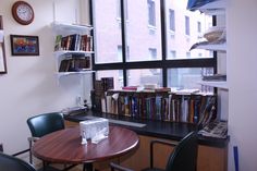 a table with two chairs and a book shelf in front of a window filled with books