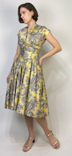 -->DESCRIPTION<-- Vintage 50s GORGEOUS golden yellow dress with matching bolero! So classic, slightly drop waist cut with full crinoline skirt and bow and rhinestone detail. Love the oversized paisley print and dreamy, almost southwest colour scheme. The bolero can be worn separately as a low cut crop top! No tags, dress is fully lined, does up with a steel zipper. -->CONDITION<-- Pristine condition! -->FABRIC<-- No tag to indicate, has a slight sheen, feels like a brushed cott Fitted Yellow Dress With Pleated Bodice, Yellow Fitted Dress With Pleated Bodice, 1950s Style Yellow Dress For Garden Party, Vintage Yellow Dress For Garden Party, Yellow 1950s Style Dress For Garden Party, Yellow Vintage Dress For Garden Party, Yellow Retro Vintage Dress For Garden Party, Fitted Dress With Vintage Pattern For Vintage Events, Fitted Yellow Dress In 1950s Style