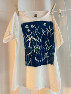 a t - shirt hanging on a clothes line in front of a shower curtain with bamboo leaves painted on it