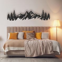 a bed sitting under a wall with mountains on the top of it's headboard