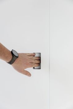 a person's hand is touching the wall with an electronic device in their left hand