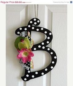 a black and white polka dot monogrammed door hanger with flowers on it