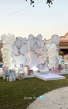 a birthday party with balloons and presents on the grass in front of a large balloon arch