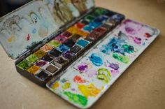 an artist's palette with watercolors on it sitting on top of a table