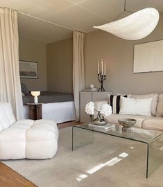 a living room filled with furniture and a glass coffee table in front of a bed