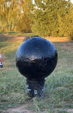 a large black ball sitting on top of a fire hydrant in the middle of a field