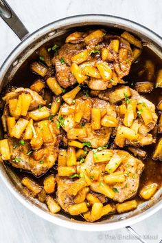 a pan filled with meat and potatoes on top of a white countertop next to a spoon