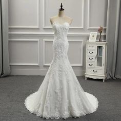 a wedding dress on display in front of a white wall