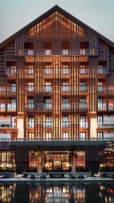 the building is lit up at night with lights reflecting in the water on the surface