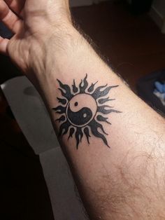 a man's arm with a tattoo on it that has a ying - o in the middle