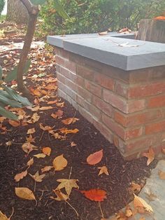 a fire hydrant sitting on top of a pile of leaves next to a brick wall