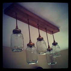 four mason jars hanging from a wooden beam