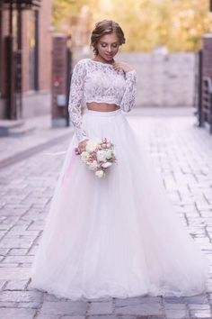 a woman in a white wedding dress standing on a brick road