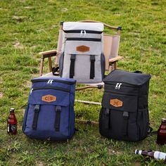 three cooler bags sitting on top of a grass covered field next to two beer bottles