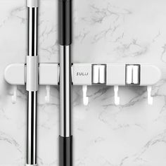 two chrome and white bathroom fixtures on a marble wall with three metal bars attached to it