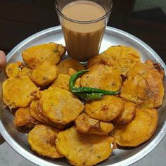 a silver plate topped with fried food next to a cup of coffee