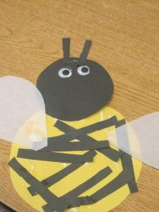 a paper cut out of a bee sitting on top of a wooden table