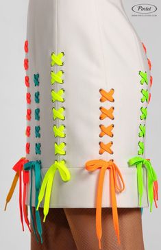 the back of a woman's skirt with neon colored laces and bows on it