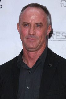 a man in a black shirt and blazer posing for a photo on the red carpet