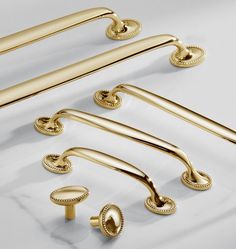 an assortment of brass handles and knobs on a white surface, including the handle