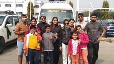 a group of people are standing in front of a bus with their arms around each other