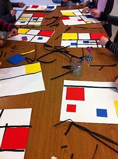 several children are sitting at a table making art with paper squares and colored pencils