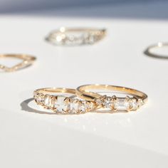 three different types of wedding rings sitting on a table next to each other, with one diamond set in the middle