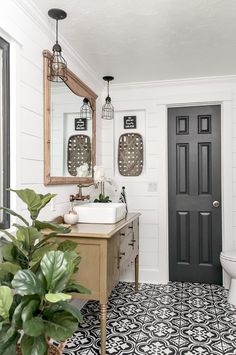 a bathroom with black and white tile flooring, a mirror, sink and toilet