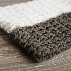 a close up view of a crocheted blanket on a wooden surface with white and brown colors