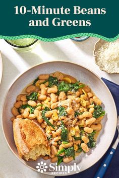 a white bowl filled with beans and greens next to bread on top of a table