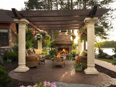 an outdoor living area with chairs, tables and a fire place in the middle of it