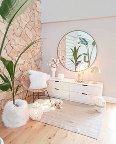 a living room with white furniture and a large round mirror on the wall above it