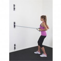 a woman is using a pull up bar to do exercises on the floor in front of a white wall