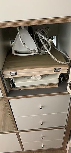 an ironing board sitting on top of a dresser next to a corded iron