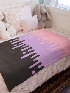 a bed with pink and black comforter on top of it next to a stuffed animal