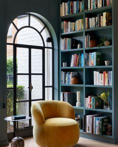 a living room filled with lots of books and furniture next to a large open window