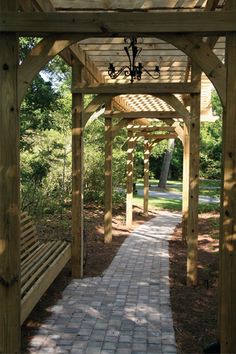 a wooden bench sitting under a pergoline covered gazebo next to a brick walkway