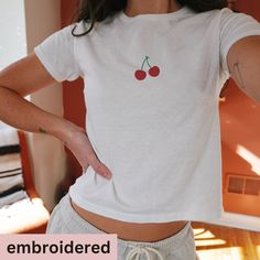 *Please note, holiday shipping times may be longer than normal. Please allow at least 7 days for shipping*  embroidered crop top with Cherries. This is a slim fit, for a looser fit, we recommend sizing up.  Product details  * 52% combed ring-spun cotton, 48% polyester * 40 singles * Slim fit RETURNS OR EXCHANGES All of our shirts are custom printed to order, made just for you, so we do not accept returns or exchanges due to color or fit/size. If there are any issues with the shirt, please messag Trendy Embroidered Summer T-shirt, Cute White Cotton Cropped T-shirt, Fitted Cotton T-shirt With Cherry Print, Fitted Short Sleeve T-shirt With Cherry Print, Fitted Short Sleeve Cherry Print T-shirt, Fitted Cherry Print T-shirt With Short Sleeves, Fitted Cherry Print Short Sleeve T-shirt, Fitted Cherry Print T-shirt For Summer, Cute Short Sleeve Summer Crop Top