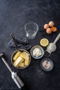 ingredients to make an appetizer laid out on a black counter top, including eggs and butter