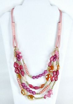 Pink multi strand four row necklace has a mix of genuine glass, stone and acrylic beads on a pink satin cord.  Necklace has    various shades of pink, tangerine, and  gold tone beads and stones.  Graduated overall length is 22".  Necklace has a lobster  claw clasp for closure with a 3" gold tone chain extension.  Gorgeous necklace for Society, and Pink - Red Hat ladies.   Excellent quality. Item #318P Pink Multi-strand Faceted Beads Jewelry, Pink Multi-strand Jewelry With Faceted Beads, Adjustable Multi-strand Pink Jewelry, Pink Multi-strand Beads For Jewelry Making, Pink Adjustable Multi-strand Necklace, Adjustable Double Strand Pink Jewelry, Pink Bohemian Multi-strand Necklaces, Bohemian Multi-strand Pink Necklace, Bohemian Pink Multi-strand Beads